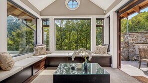 Un intérieur moderne avec une grande fenêtre, une table basse en verre et un mur en pierre.