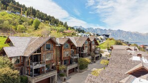 Ein Wohngebiet an einem Hang mit Holzhäusern, die Balkone und große Fenster haben, vor einer Bergkulisse.