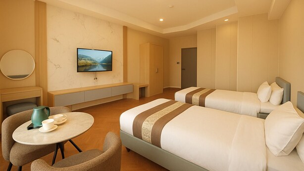 A hotel room with two beds, a TV, a desk, and a chair. - Misoko hotel (Ulaanbaatar)