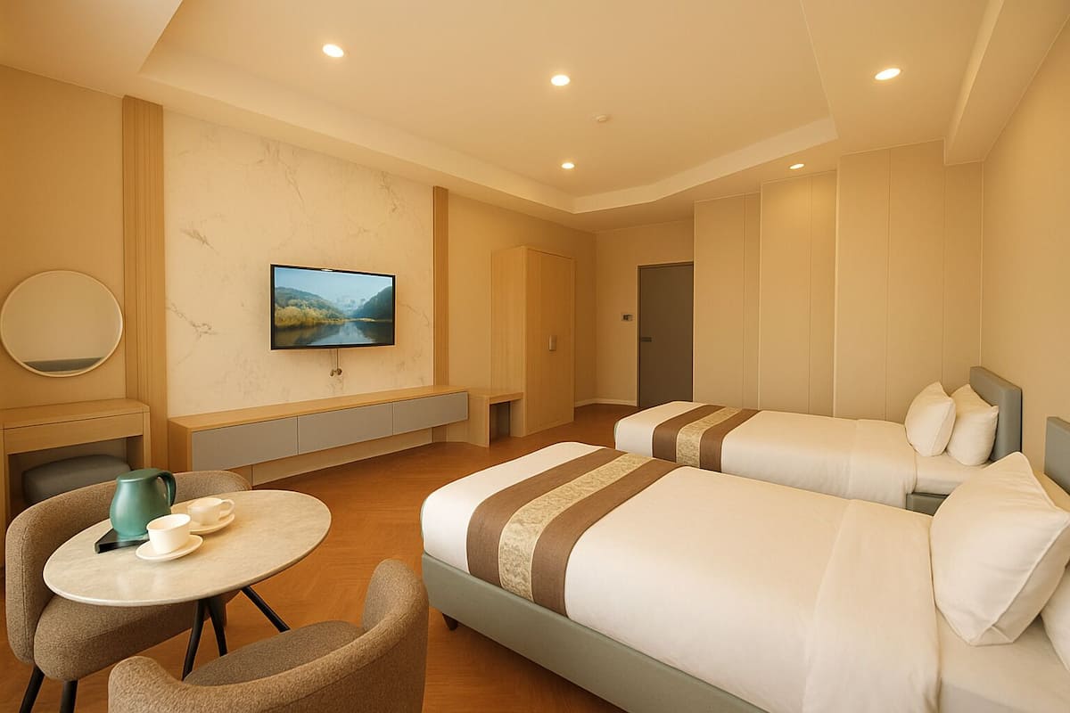 A hotel room with two beds, a TV, a desk, and a chair.