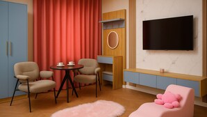 A modern living room with a TV, two chairs, a small table, a pink sofa, and a red curtain. - Misoko hotel (Ulaanbaatar)