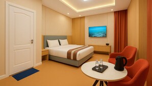A hotel room with a bed, a TV, a desk, and a table with a kettle and glasses. - Misoko hotel (Ulaanbaatar)