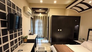 A hotel room with a bed, a desk, a television, and a wardrobe. - Virasat Haveli (Varanasi)