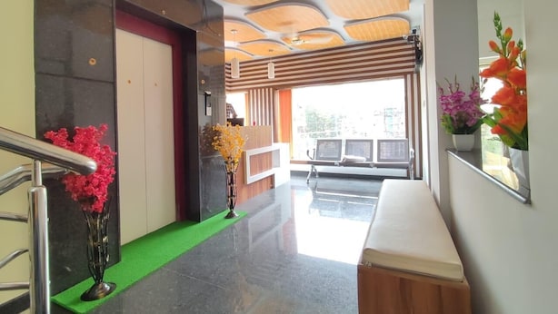A modern hotel lobby with a reception desk, a green carpet, and a bench. - Hotel Royal Suites (Bengaluru)