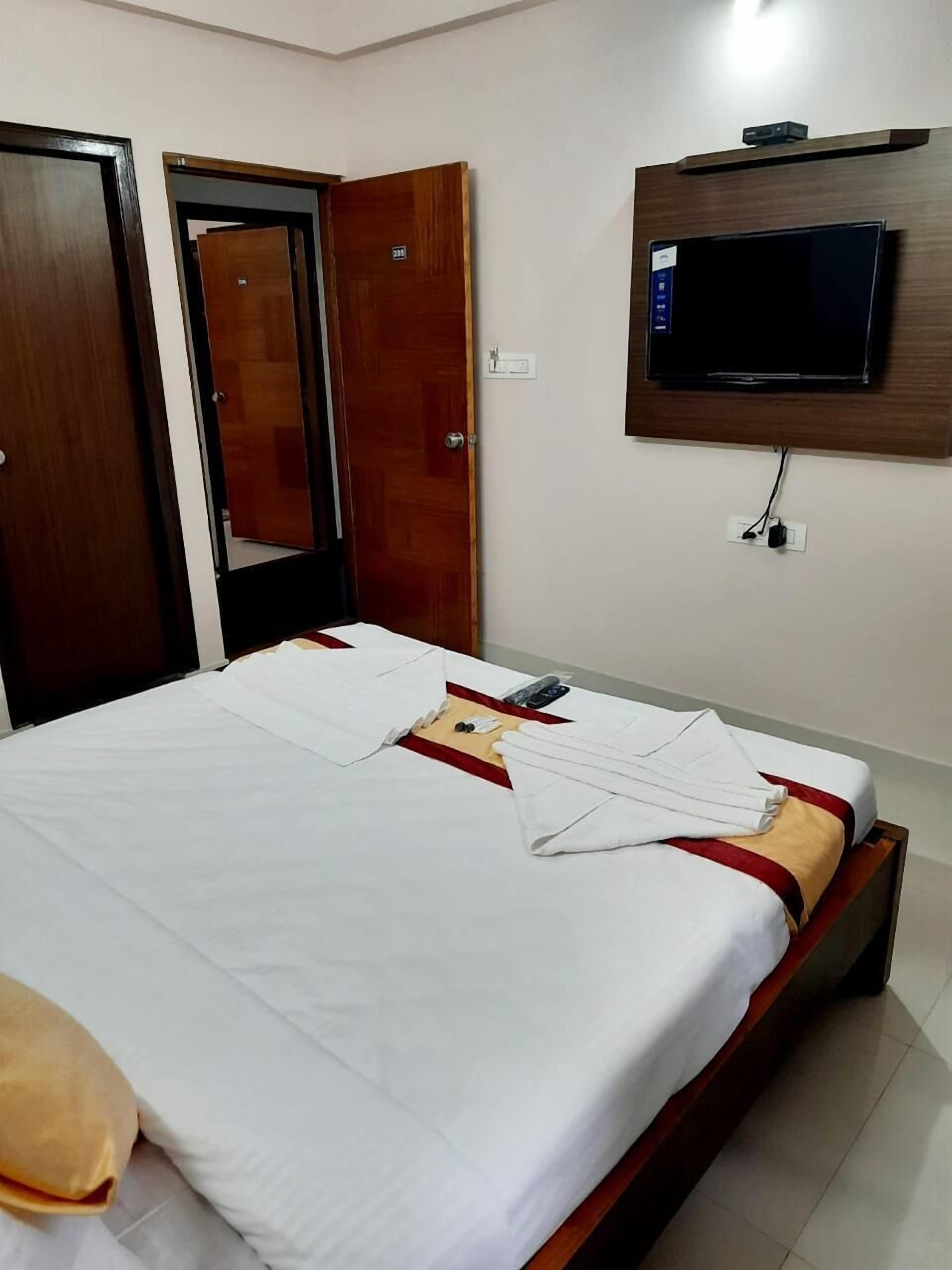 Ein Hotelzimmer mit einem Bett, einem an der Wand montierten Fernseher und einem Holzschrank.