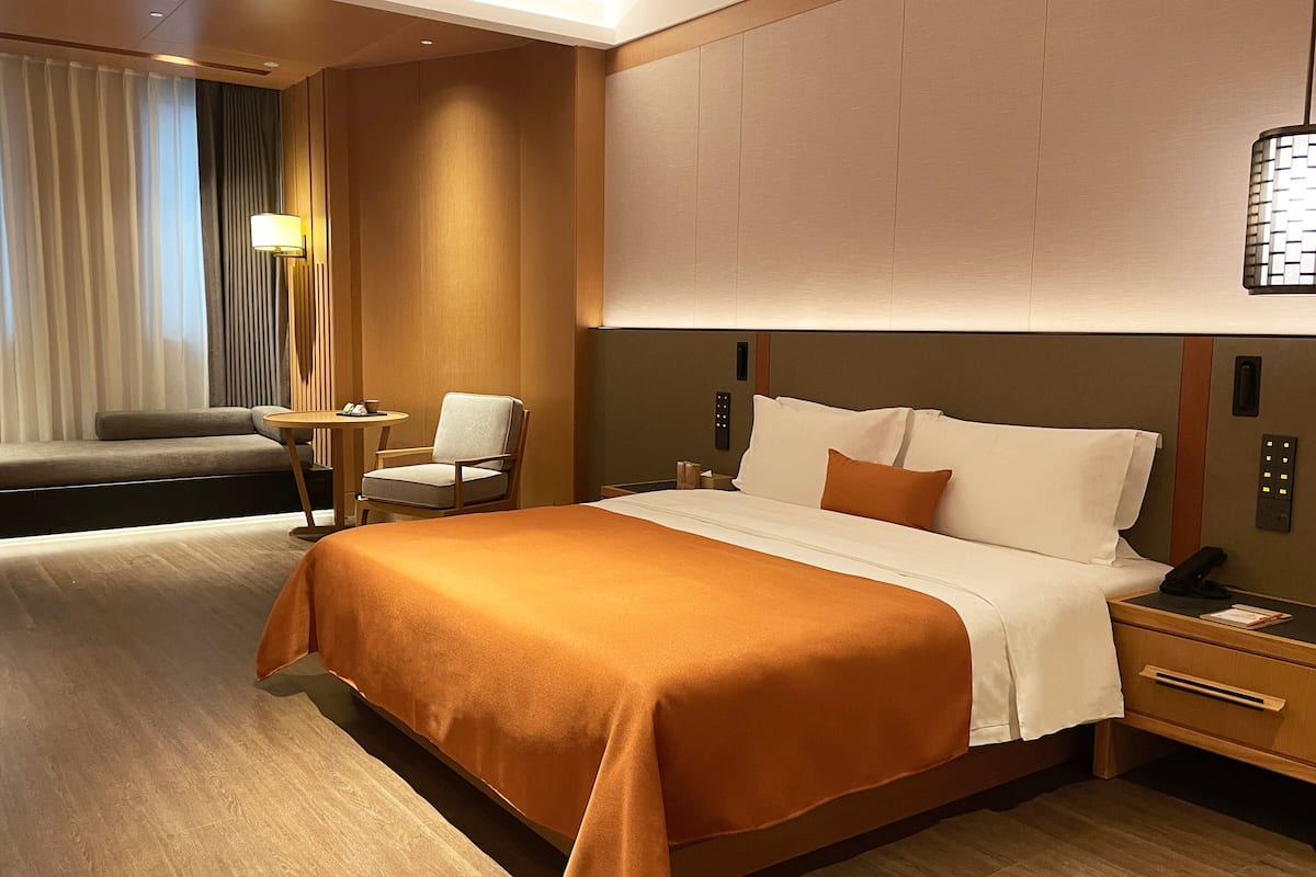 Habitación de hotel con una cama grande, un sofá, una mesita y una silla.