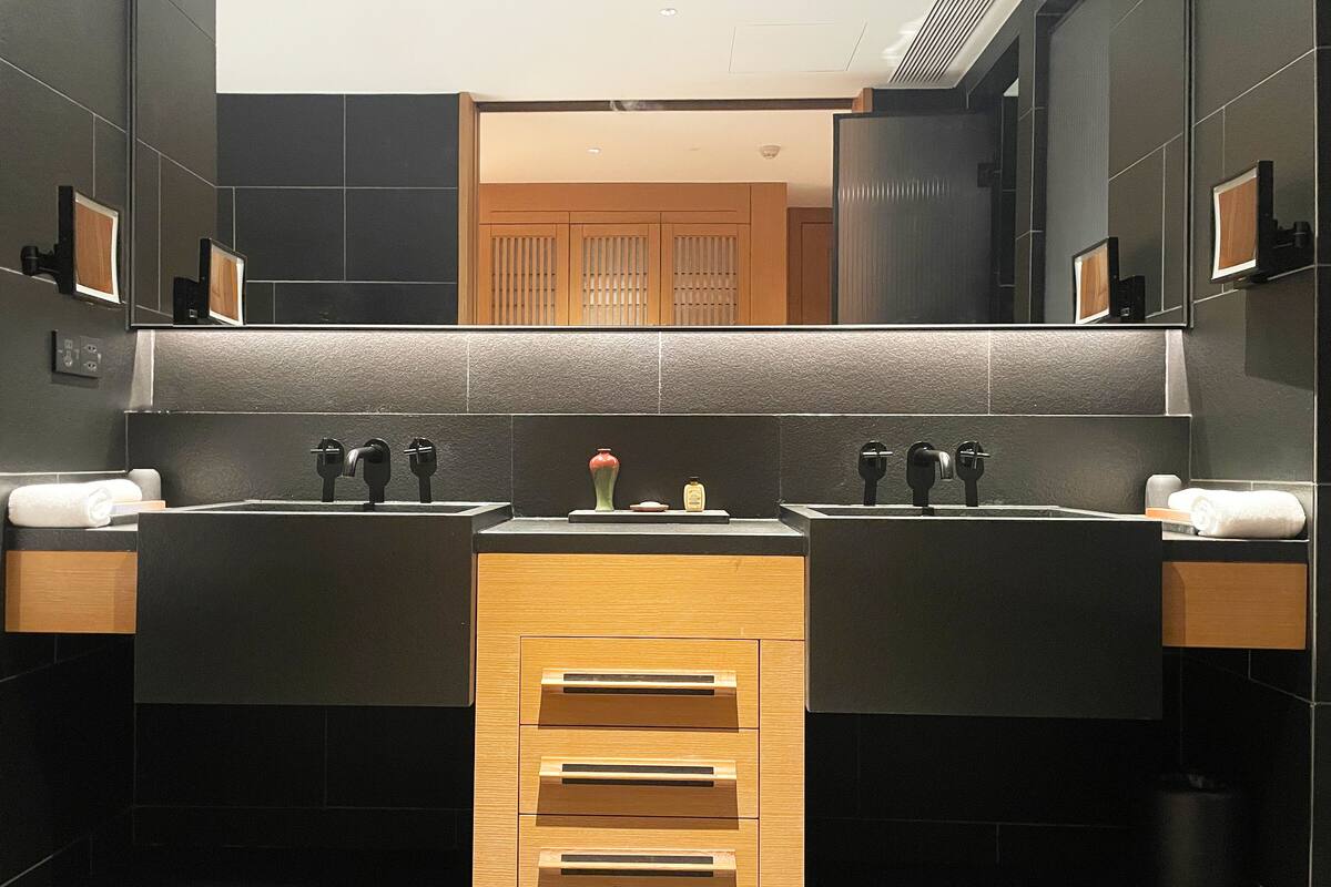 Un baño moderno con dos lavamanos, un espejo arriba y un panel de madera en el centro.