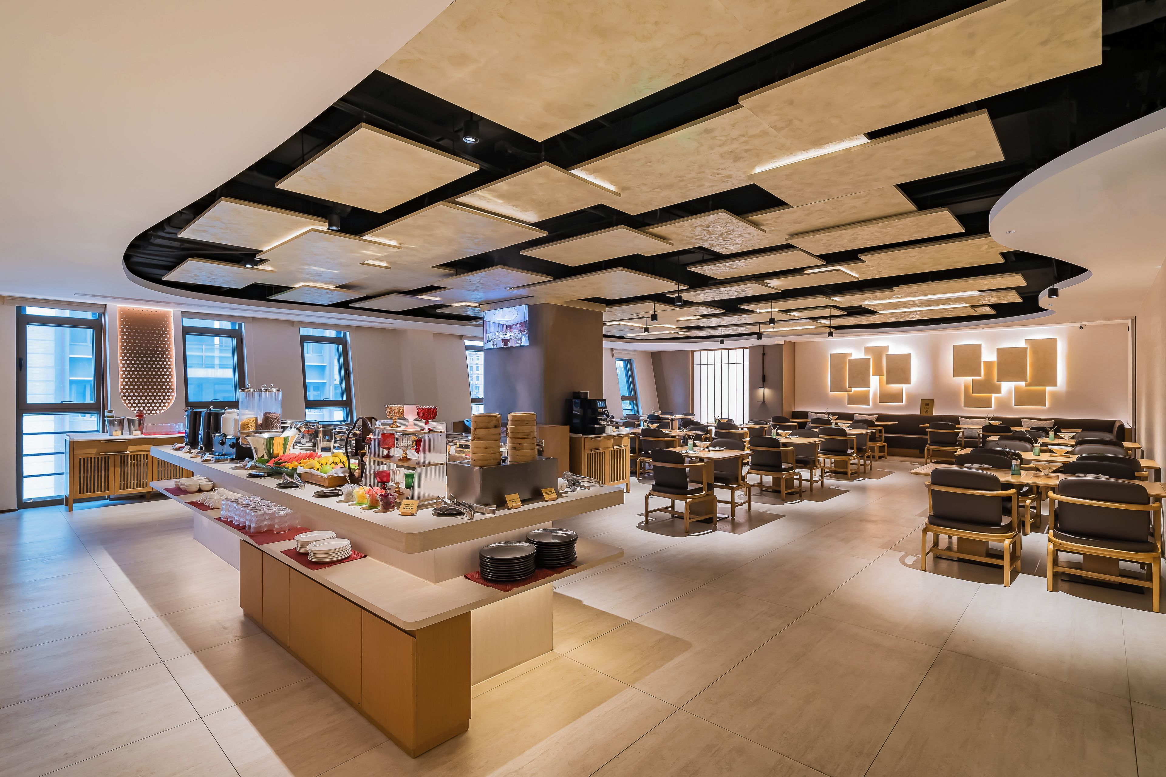 A modern dining area with a buffet setup, seating arrangements, and a ceiling with geometric patterns.