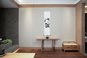 A minimalist room with a wooden desk, a bed, a wall-mounted artwork, and a potted plant. - AKENO Hotel (Beijing)