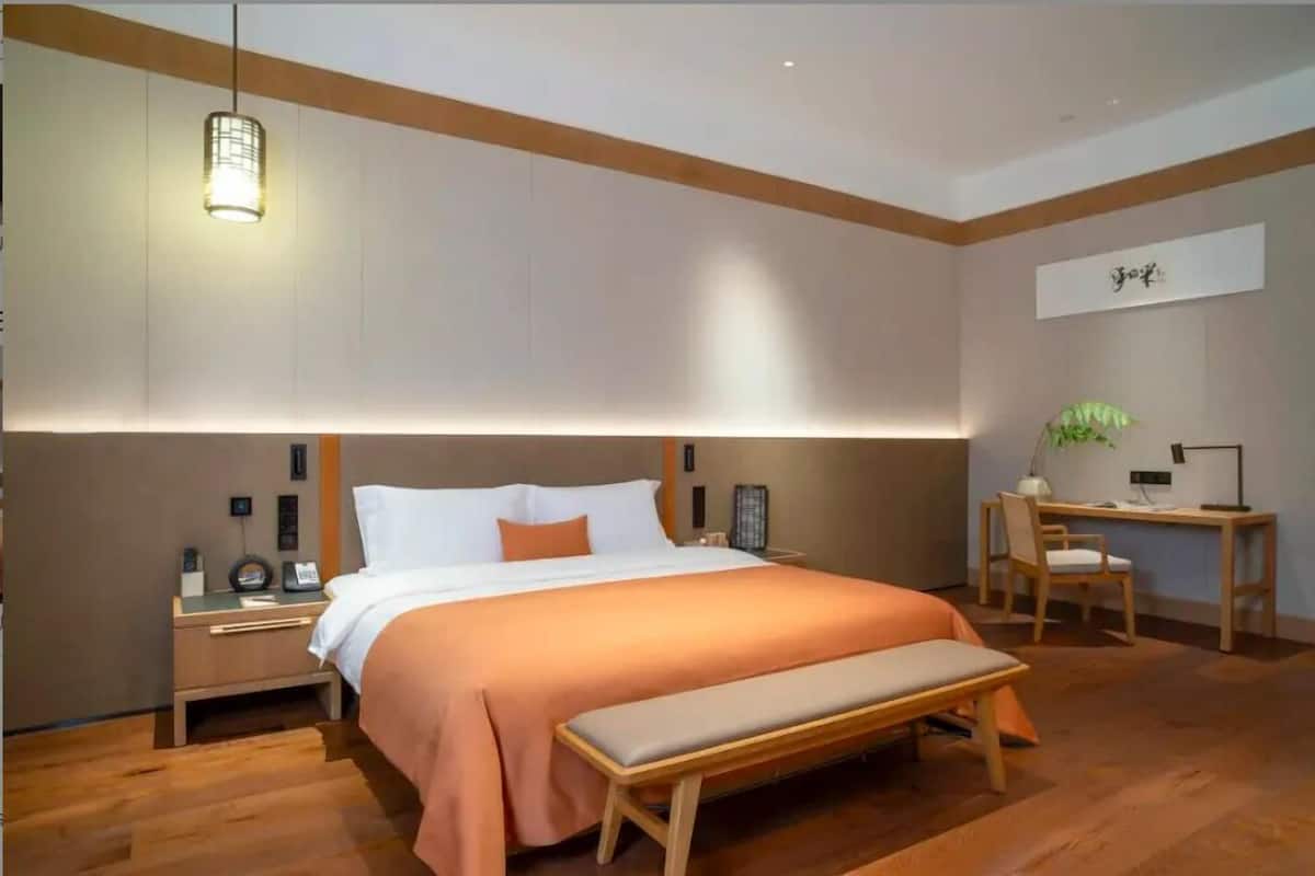 Un dormitorio moderno con una cama grande, un banco, un escritorio y una silla.