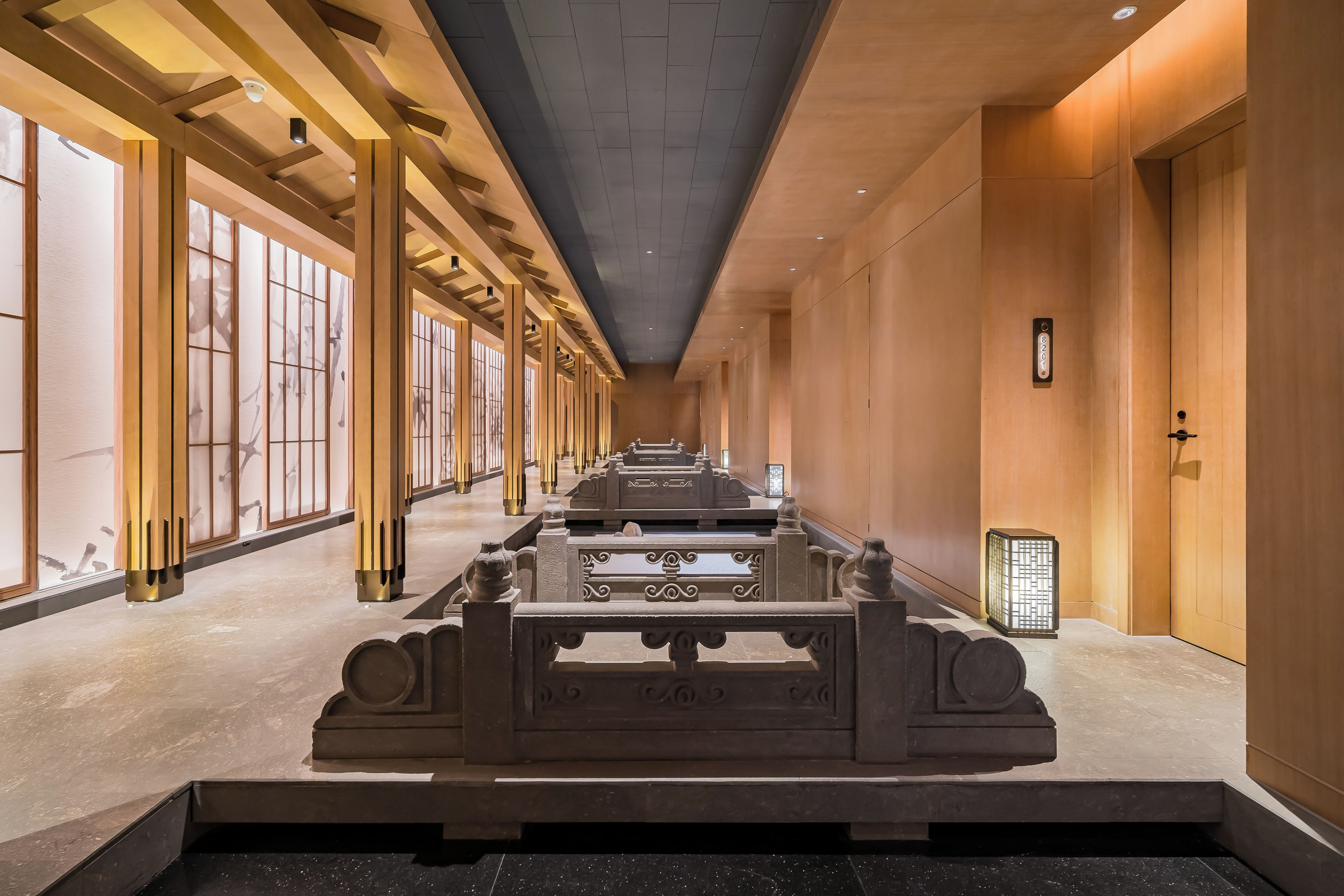 A hotel corridor with a long reception desk, wooden paneling, and a tiled floor.