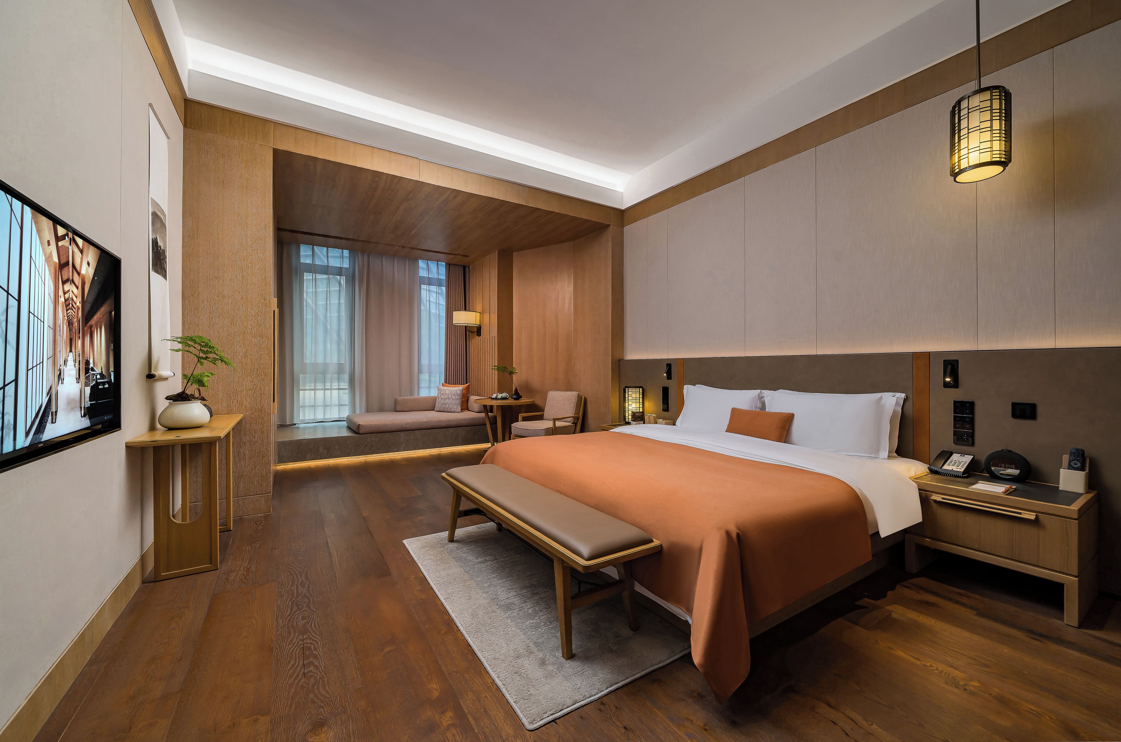 A modern hotel room with a large bed, bedside tables, a desk, and a seating area with a view.