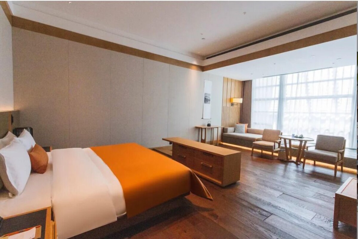 A hotel room with a bed, a desk, a sofa, and a chair.