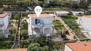 Une villa moderne avec une façade en pierre, un balcon et un petit jardin.