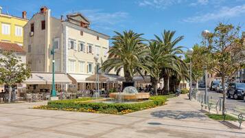 A public square with a fountain, palm trees, and outdoor seating at a café.