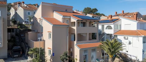 Um bairro residencial com telhados de telha de barro, escadas de pedra e um carro estacionado.