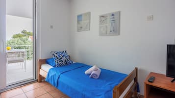 A bedroom with a bed, a TV, a desk, and a balcony.