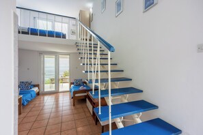 Une pièce à plusieurs niveaux, avec un escalier, un balcon et un lit avec une literie bleue.