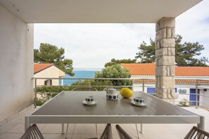 A balcony with a table set for two, a yellow lemon, and a view of the sea and buildings. - Valdarke Vittorio Apt With Sea View Terrace (Mali Losinj)