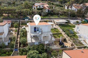 Une villa moderne avec une façade en pierre, un balcon et un petit jardin.