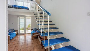 Une pièce à plusieurs niveaux, avec un escalier, un balcon et un lit avec une literie bleue.