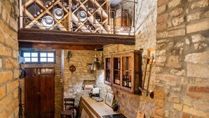 Una cocina rústica con paredes de piedra, encimera de madera y una bodega.