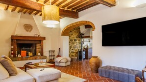Una sala de estar con chimenea, sofá, reposapiés y televisión montada en la pared.