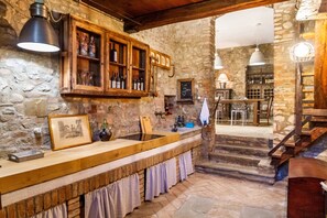 Un coin bar au style rustique, avec des murs en pierre, des étagères en bois et un grand évier.