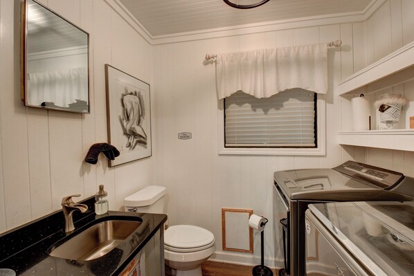 Een badkamer met een wastafel, toilet en een in glas gezet wasmachine.