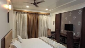 Une chambre d’hôtel équipée d’un lit, d’un bureau, d’une chaise, d’une télévision et d’un ventilateur de plafond.