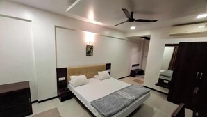 Une chambre à coucher moderne, équipée d’un lit, d’un ventilateur de plafond, d’une table de chevet et d’une armoire.