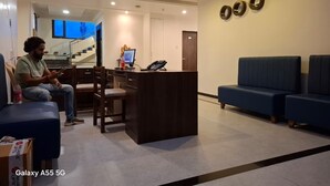Un hall d’hôtel comprenant un comptoir d’accueil, un espace salon et un escalier menant à l’étage supérieur.