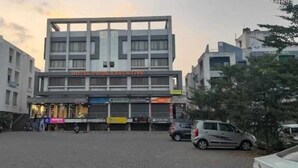 Un hôtel à plusieurs étages, avec une enseigne bien visible indiquant « Hotel Pride Executive », et plusieurs boutiques en devanture.