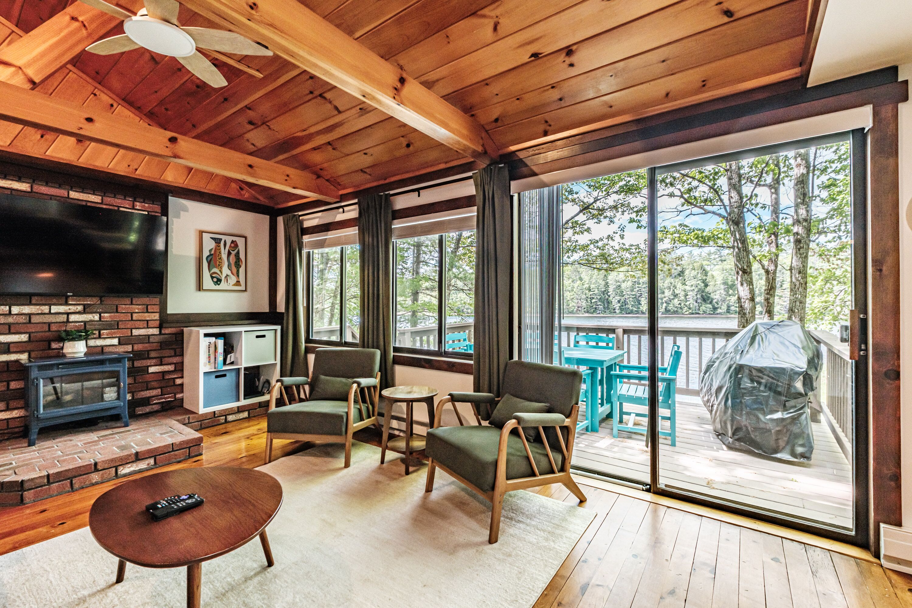 A wooden interior with a TV, seating, and a view of the outdoors.