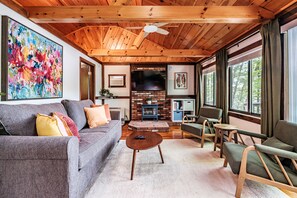 Un salon chaleureux avec une cheminée, un plafond en bois et de grandes fenêtres.