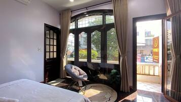 A hotel room with a bed, a chair, a large window, and a view of the outside.