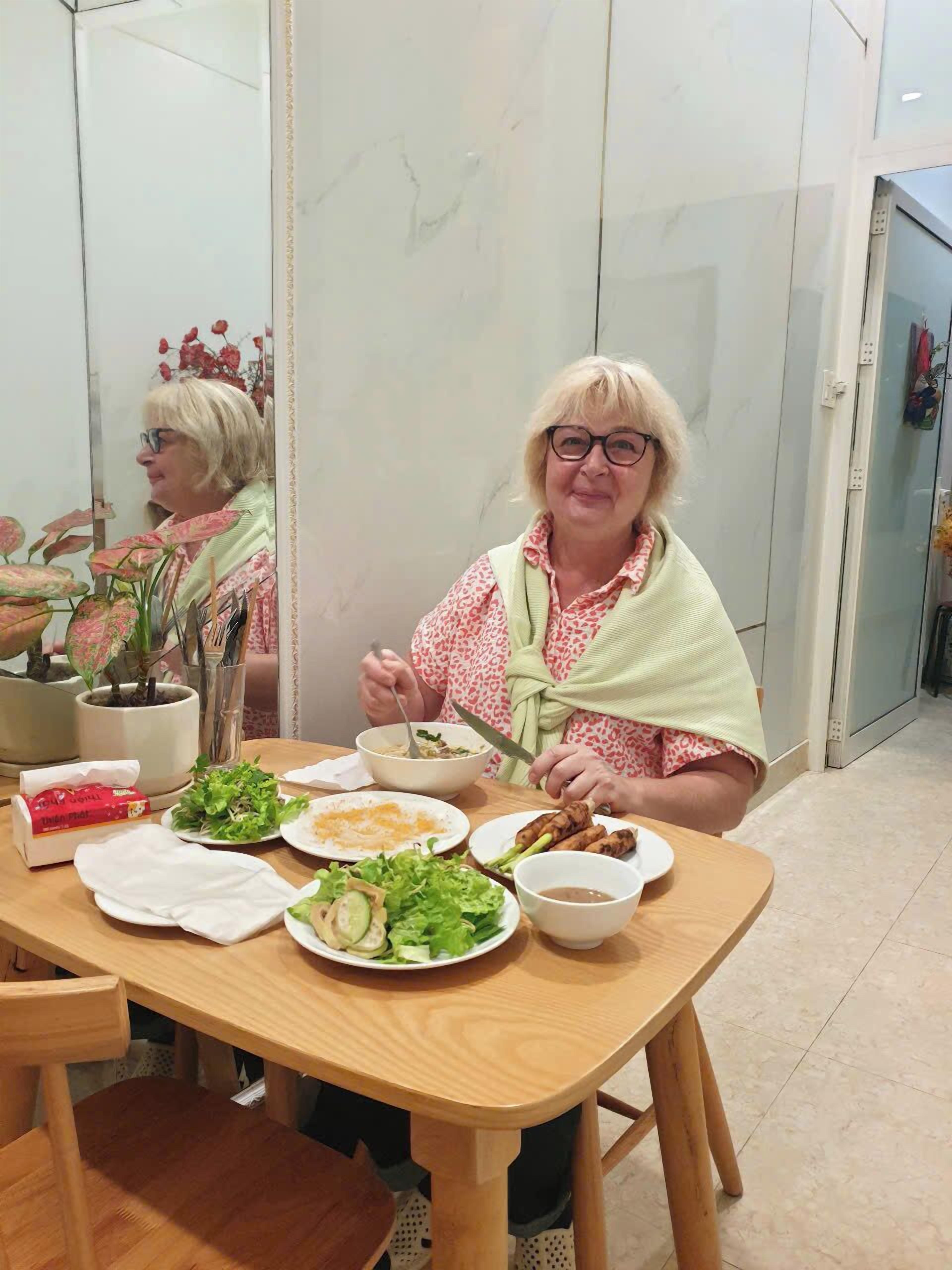 Una mesa de comedor con varios platos, una planta en maceta y una persona comiendo.
