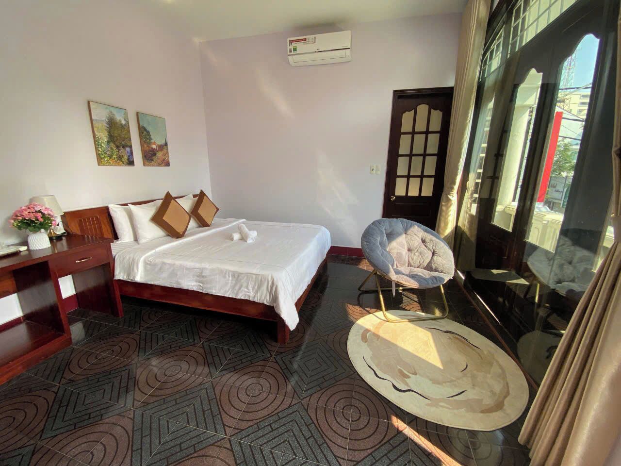 Ein Hotelzimmer mit einem Bett, einem Sessel, einem Schreibtisch und einem großen Fenster.