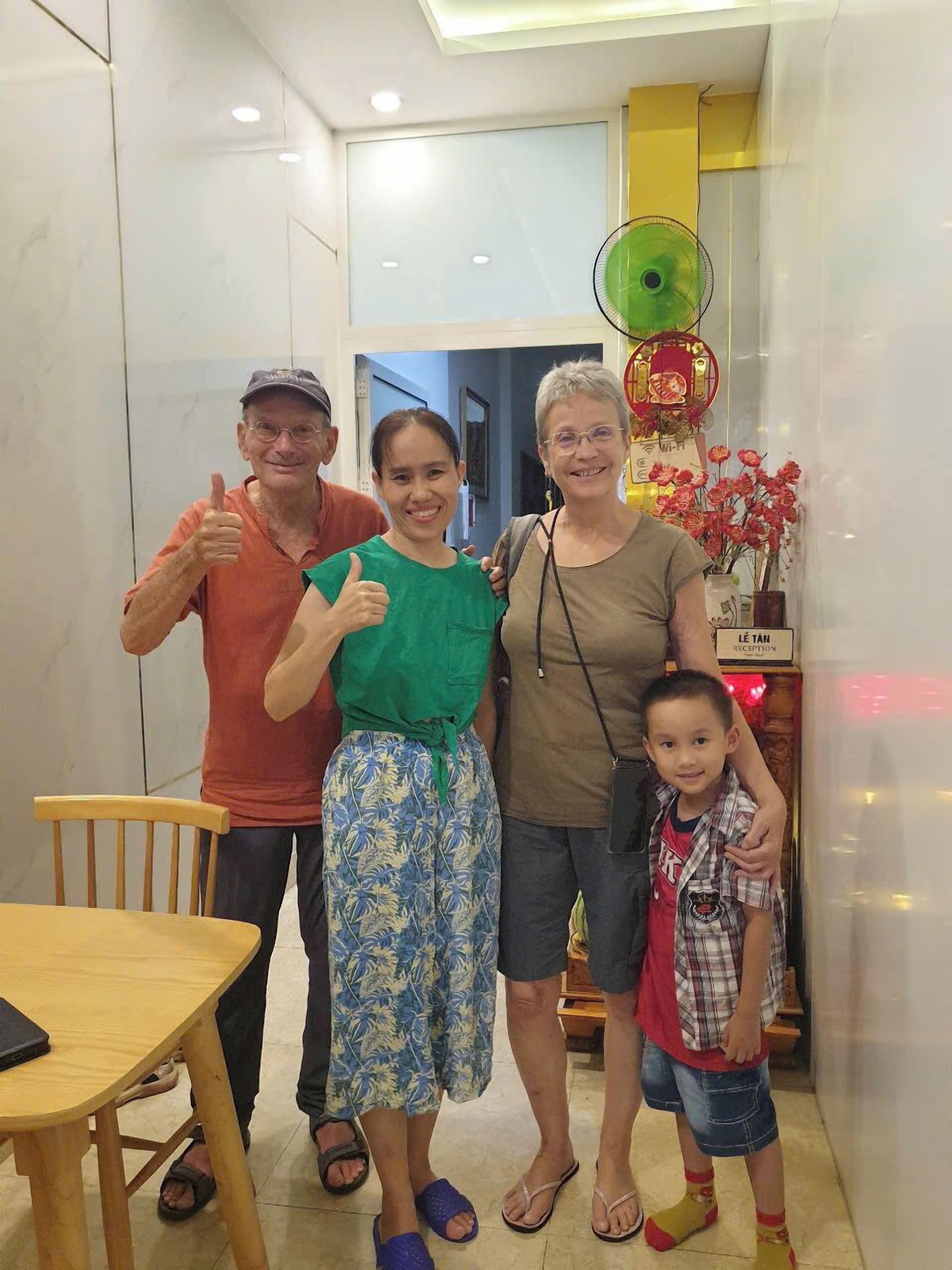A family of four in a modern interior with a reception desk and a green fan.