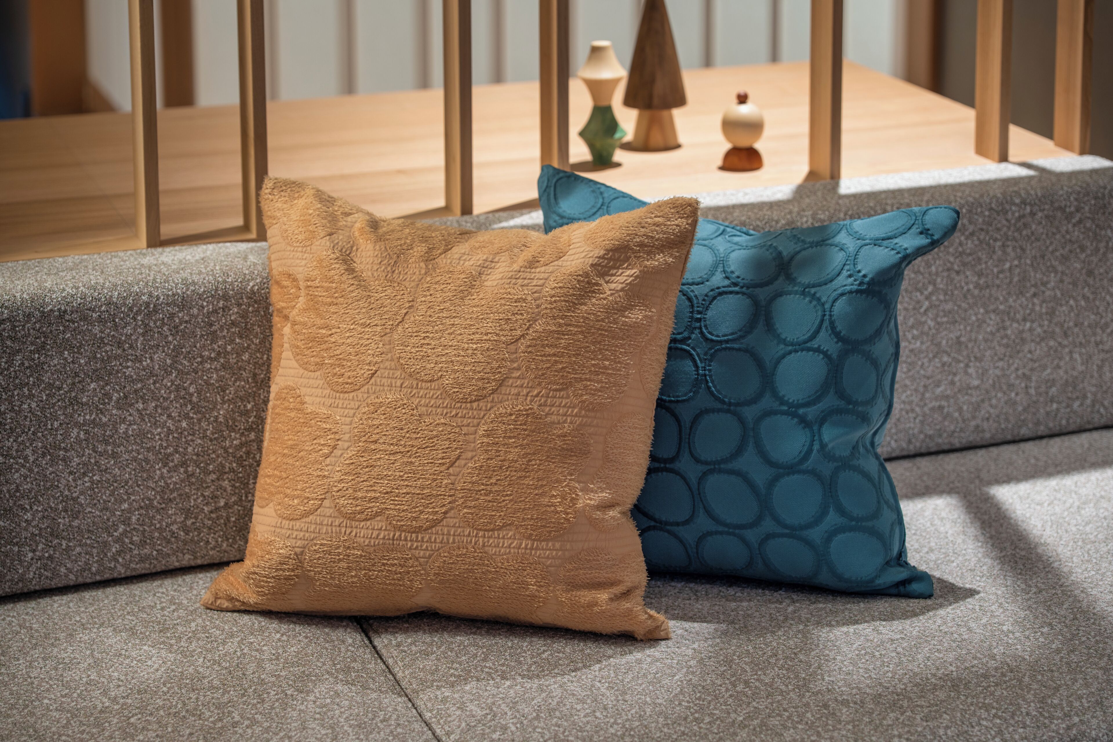 En sofa med to puder, hvoraf den ene har et struktureret mønster og den anden et cirkulært design.