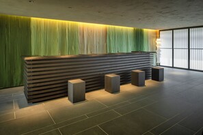 A reception desk with a modern design, flanked by vertical blinds and a large window. - Hoshino Resorts KAI Kusatsu (Kusatsu)
