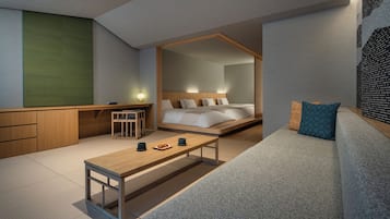 A modern hotel room with a bed, a desk, a sofa, and a dining table.