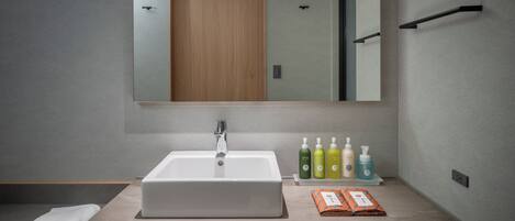 A modern bathroom with a large mirror, a sink, and a shelf with toiletries.