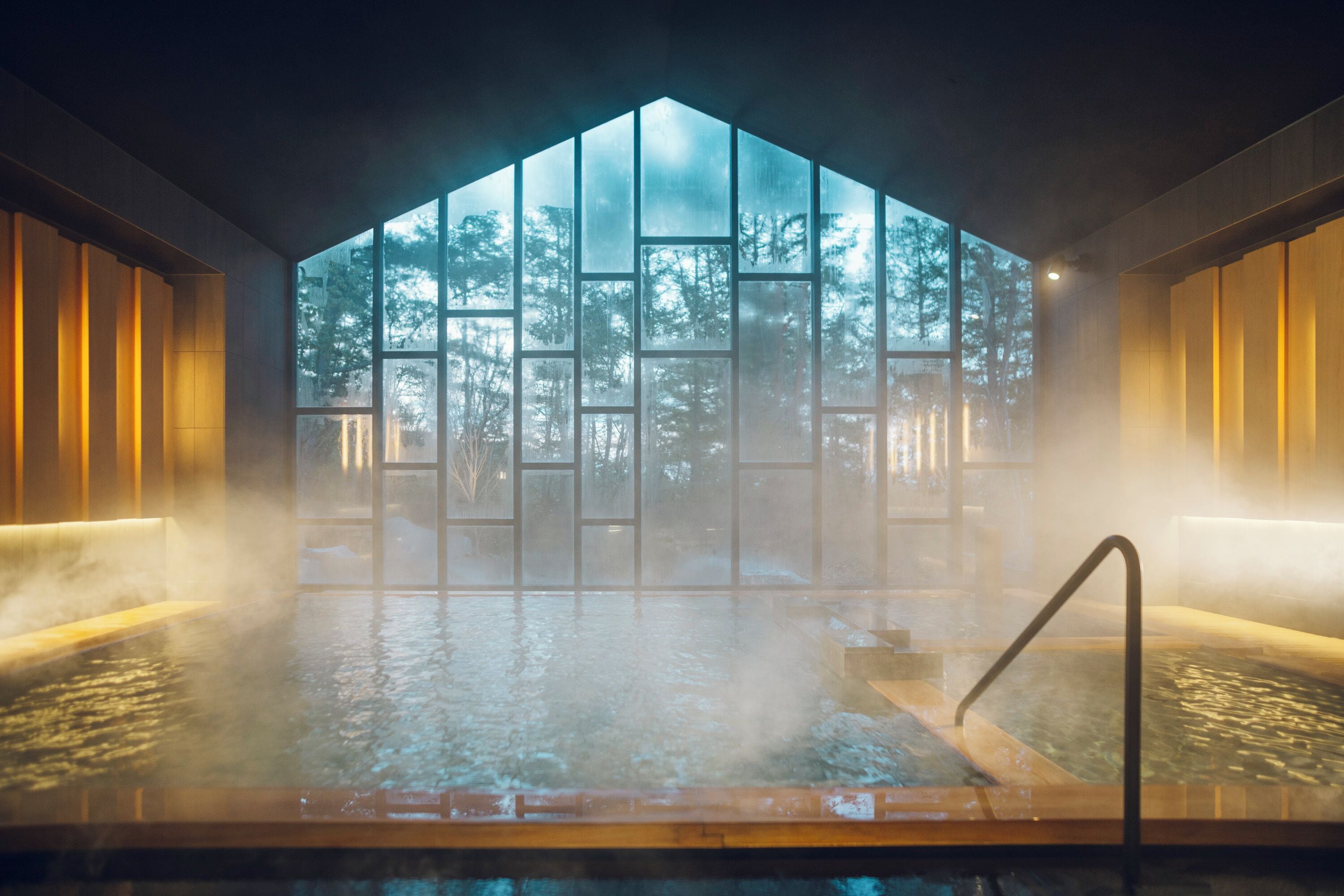 A hot tub with a view of a forest through a large window.