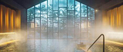 A hot tub with a view of a forest through a large window.
