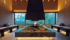 A modern interior with a central fire feature, seating areas, and large windows. - Hoshino Resorts KAI Kusatsu (Kusatsu)