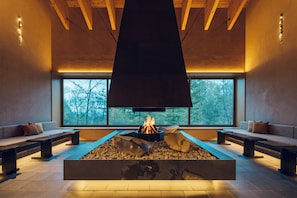 A modern interior with a central fire feature, seating areas, and large windows. - Hoshino Resorts KAI Kusatsu (Kusatsu)