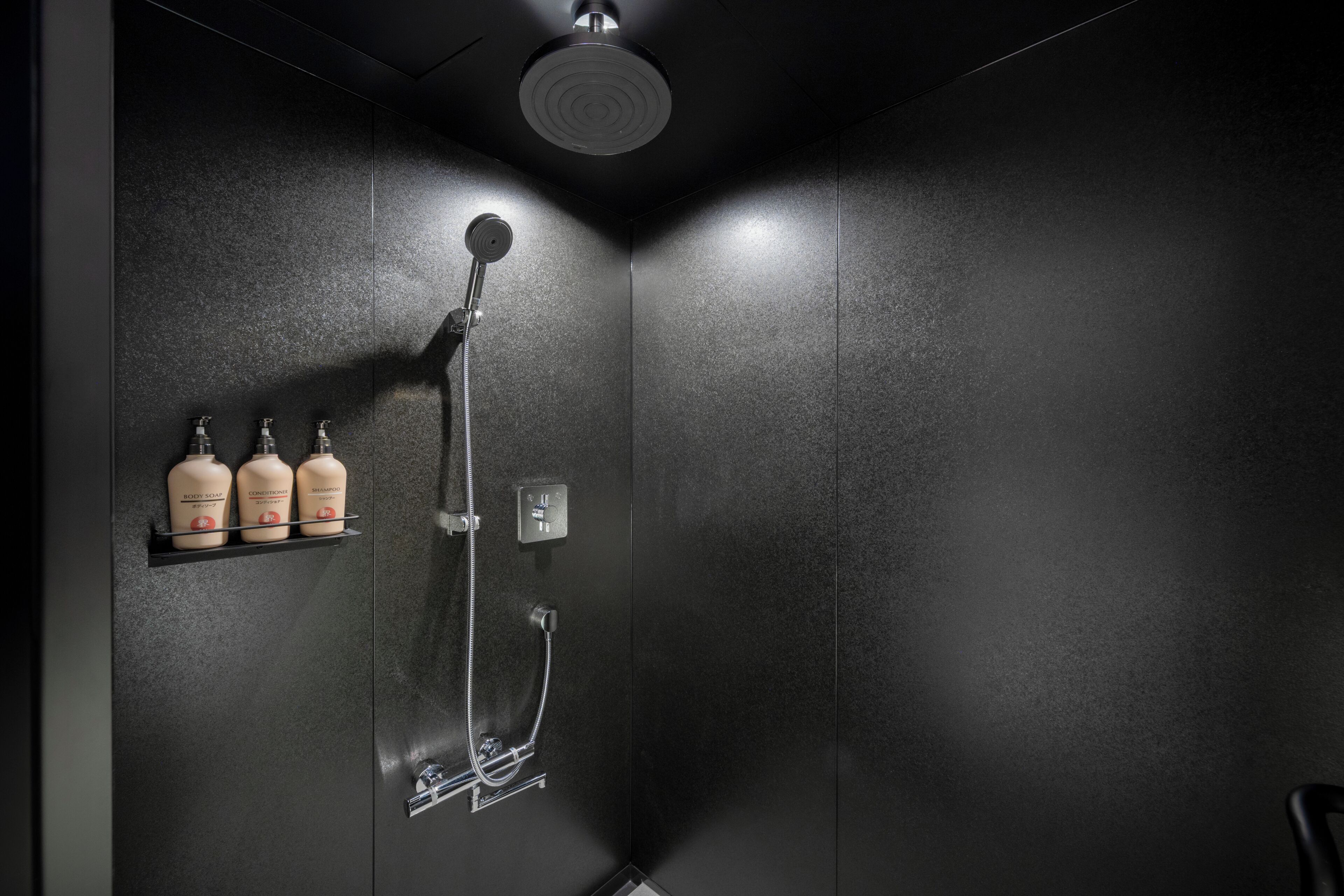 A modern shower with a handheld showerhead and a wall-mounted control panel.