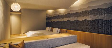 Un dormitorio moderno con cama, zona de estar y una pared con diseño de montaña.