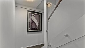 Ein Flur mit einem Bilderrahmen, der einen Vogel zeigt, einer Tür mit Griff und einem Teppichboden.